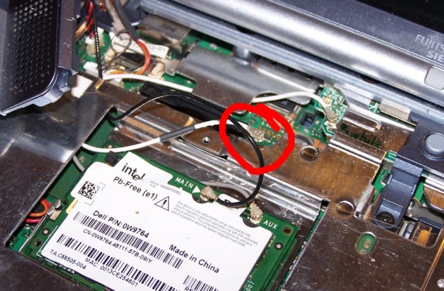 Die Mini-PCI-WLAN-Karte im geöffneten Notebook, ein rot markiertes Antennenkabel hängt lose neben dem Anschluss.