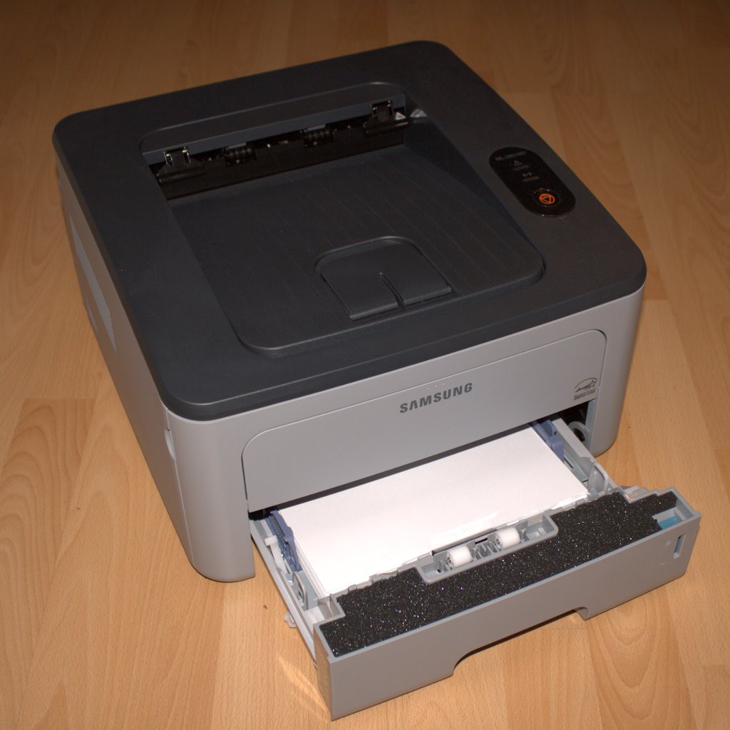 Der Laserdrucker Samsung ML-2851ND auf einem Holzboden, die Papierkassette ist ausgezogen