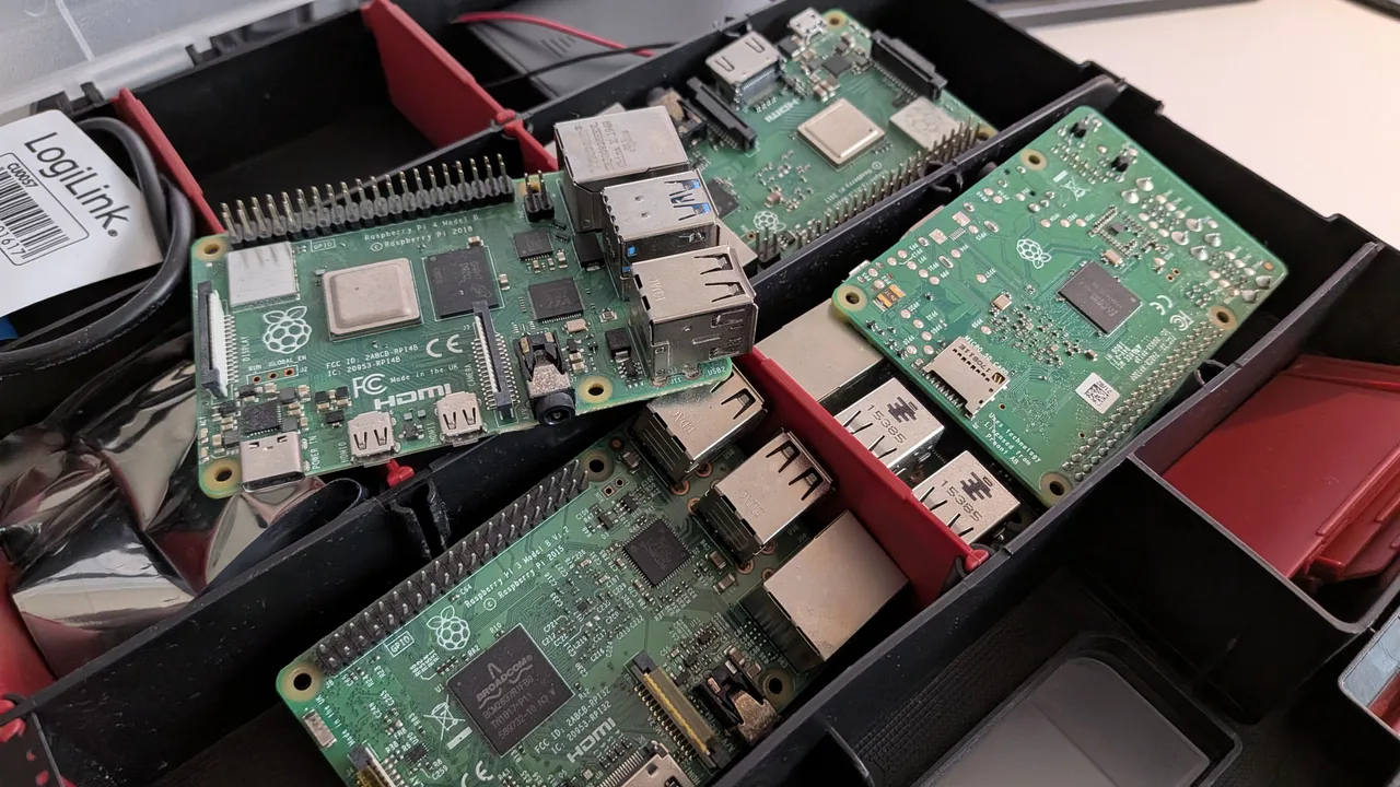 Open storage case with red dividers holding four Raspberry Pi boards, one of them upside down