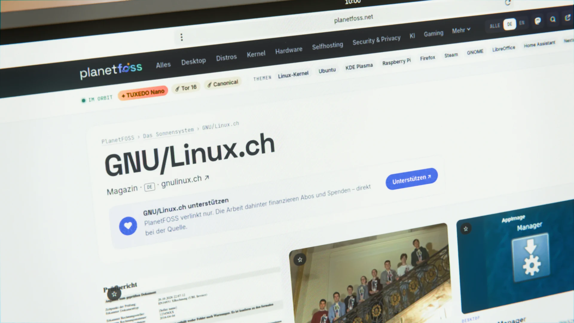 Ein schräg fotografierter Notebook-Bildschirm zeigt die Quellenseite von GNU/Linux.ch bei PlanetFOSS mit dem Kasten zum Unterstützen.