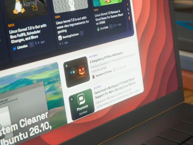 Laptop-Bildschirm zeigt Linux-Nachrichtenkarten, darunter Meldungen zum Linux-Kernel 7.3, vor rotem Hintergrund.